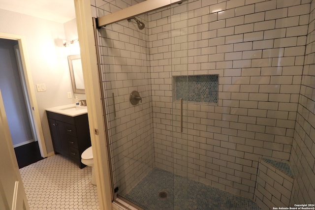 bathroom featuring vanity, toilet, tile patterned floors, and a shower with shower door