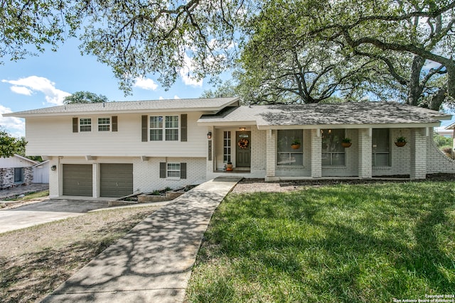 tri-level home with a garage, covered porch, and a front yard