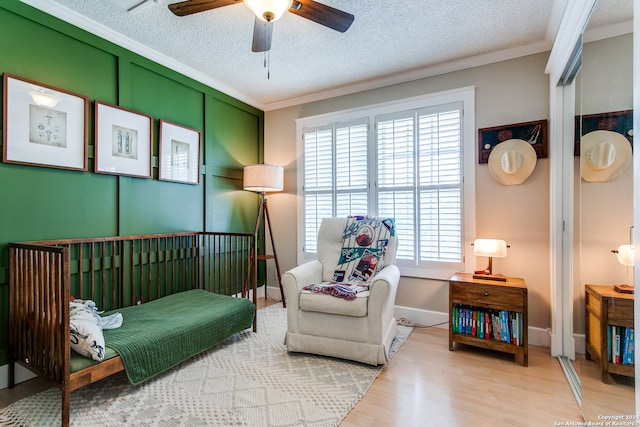 living area featuring a textured ceiling, ornamental molding, ceiling fan, and hardwood / wood-style flooring