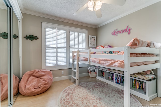 bedroom featuring a textured ceiling, wood-type flooring, ornamental molding, and ceiling fan