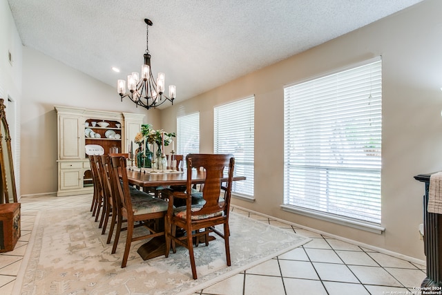 dining room with a textured ceiling, lofted ceiling, light tile patterned floors, and a chandelier