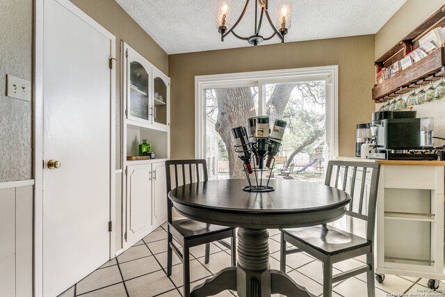 tiled dining space featuring a textured ceiling and a chandelier