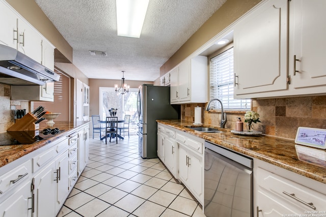 kitchen with appliances with stainless steel finishes, backsplash, white cabinetry, and a notable chandelier