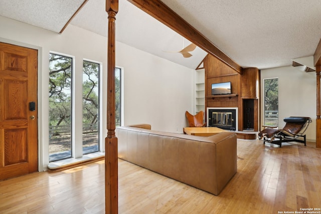 living room with lofted ceiling, light hardwood / wood-style floors, a fireplace, and a textured ceiling