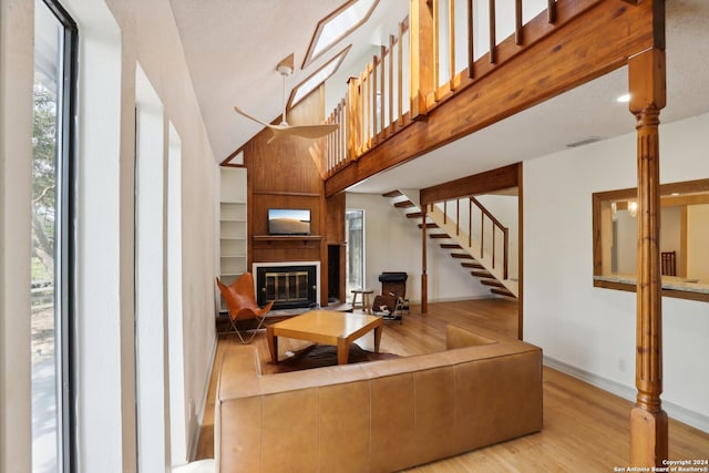 living room with high vaulted ceiling, a large fireplace, light hardwood / wood-style floors, and a textured ceiling