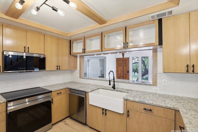 kitchen featuring light stone counters, sink, appliances with stainless steel finishes, light hardwood / wood-style floors, and decorative backsplash