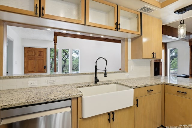 kitchen with dishwasher, light stone countertops, backsplash, and sink