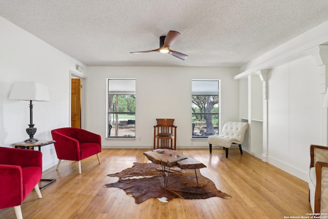 sitting room with a textured ceiling, a healthy amount of sunlight, light hardwood / wood-style floors, and ceiling fan