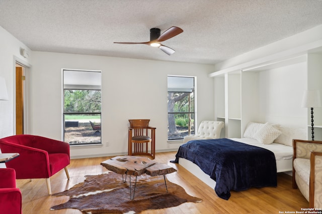 bedroom with light hardwood / wood-style floors, multiple windows, ceiling fan, and a textured ceiling