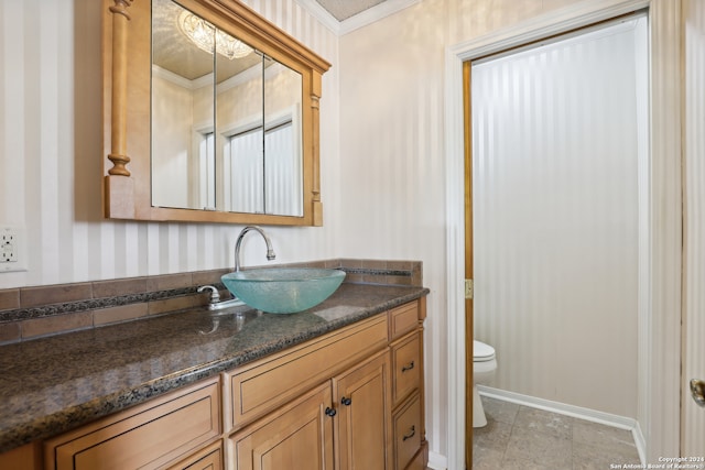 bathroom featuring tile patterned flooring, crown molding, vanity, and toilet