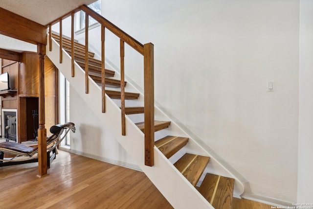 stairs with a textured ceiling and hardwood / wood-style floors