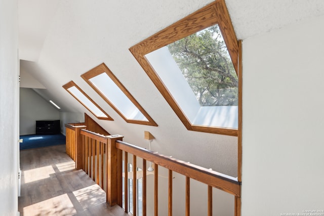 interior space with vaulted ceiling with skylight and light hardwood / wood-style flooring