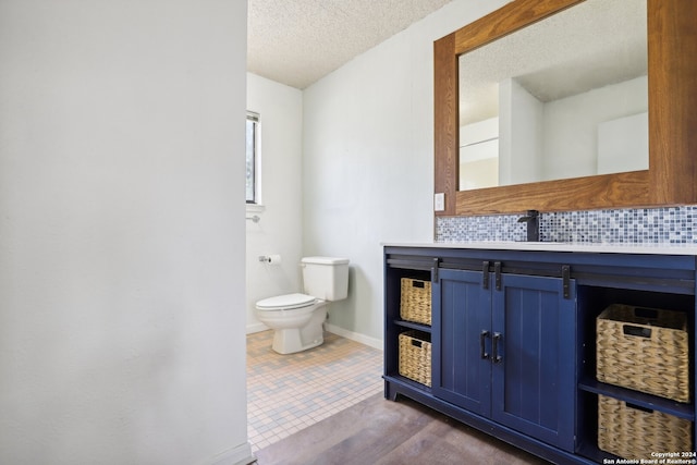 bathroom featuring decorative backsplash, a textured ceiling, vanity, and toilet