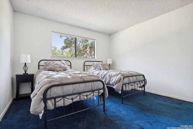 bedroom featuring a textured ceiling and dark carpet