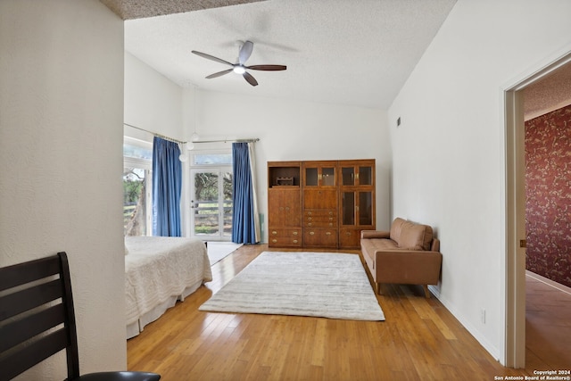 bedroom with ceiling fan, a textured ceiling, light hardwood / wood-style floors, and high vaulted ceiling