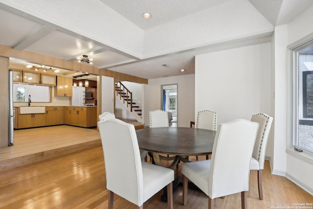 dining area with light hardwood / wood-style floors, a textured ceiling, a chandelier, and sink