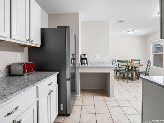 kitchen with light stone counters, white cabinets, stainless steel refrigerator with ice dispenser, and light tile patterned floors