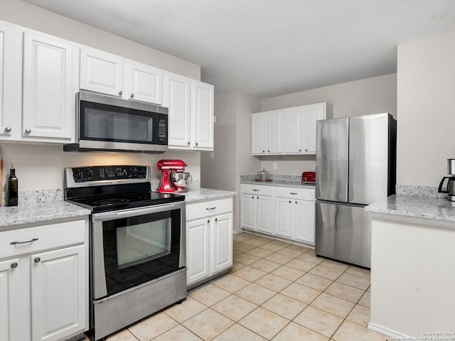 kitchen featuring light stone counters, white cabinets, light tile patterned flooring, and appliances with stainless steel finishes