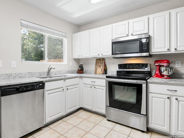 kitchen featuring light stone counters, light tile patterned flooring, sink, white cabinets, and appliances with stainless steel finishes