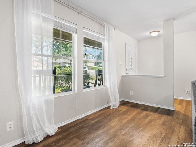 unfurnished room featuring a healthy amount of sunlight and dark hardwood / wood-style flooring