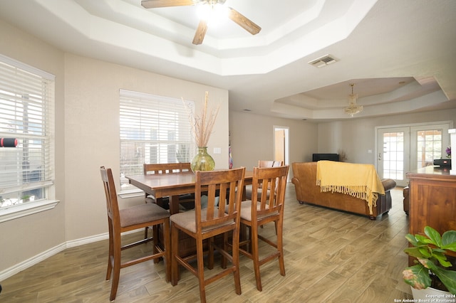 dining room with french doors, ceiling fan, light hardwood / wood-style floors, and a raised ceiling