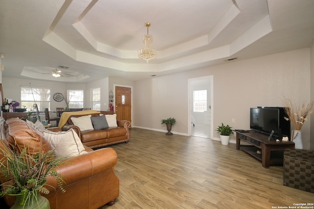 living room featuring hardwood / wood-style flooring, ceiling fan with notable chandelier, and a raised ceiling