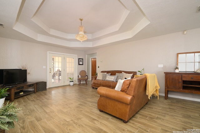 living room with an inviting chandelier, french doors, hardwood / wood-style flooring, and a tray ceiling