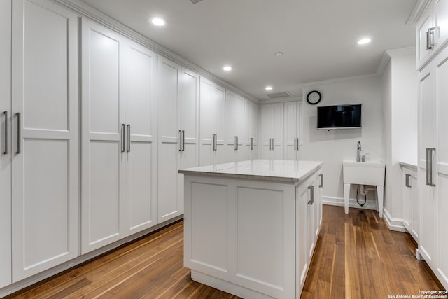 kitchen featuring light stone countertops, white cabinetry, a center island, and dark wood-type flooring