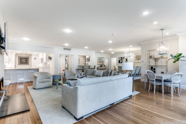 living room with crown molding, light hardwood / wood-style floors, and a chandelier