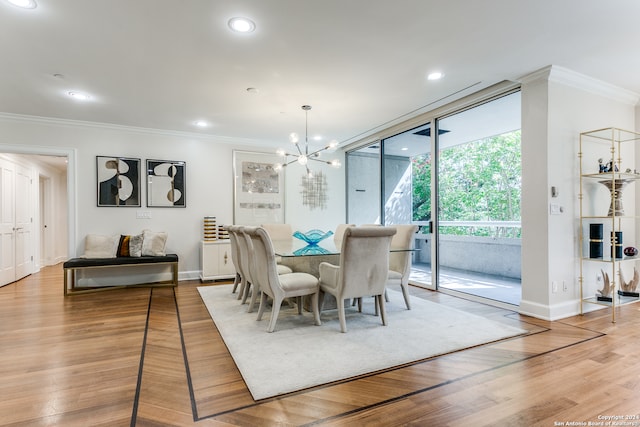 dining space featuring light wood-type flooring, ornamental molding, and a chandelier