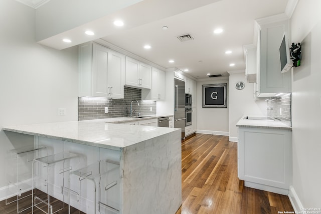 kitchen with white cabinetry, kitchen peninsula, dark wood-type flooring, and sink