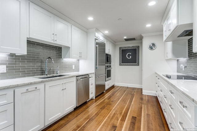 kitchen featuring backsplash, white cabinetry, hardwood / wood-style flooring, and crown molding