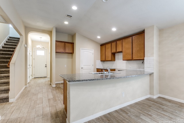 kitchen with light stone countertops, light wood-type flooring, and backsplash