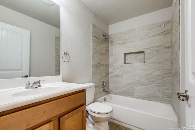 full bathroom with vanity, tiled shower / bath combo, wood-type flooring, a textured ceiling, and toilet