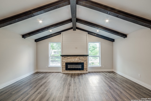 unfurnished living room featuring lofted ceiling with beams, a wealth of natural light, dark hardwood / wood-style floors, and a stone fireplace