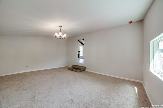 empty room featuring an inviting chandelier and carpet flooring