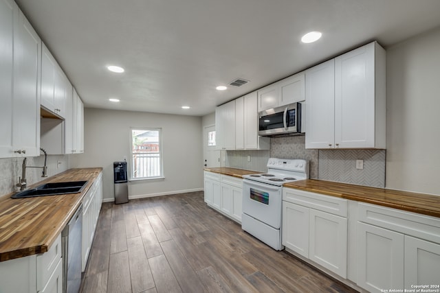 kitchen with sink, white cabinetry, stainless steel appliances, hardwood / wood-style floors, and wood counters