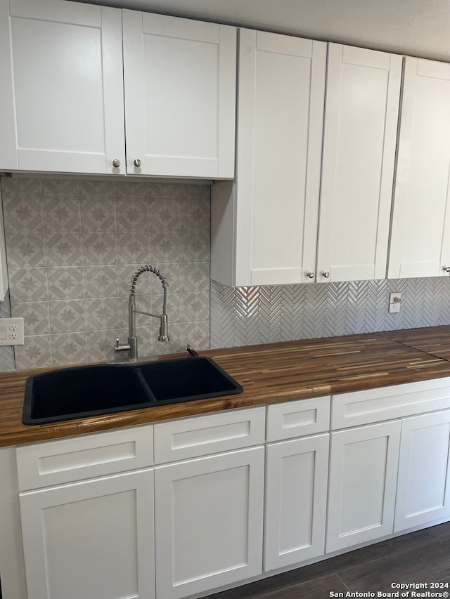 kitchen with decorative backsplash, butcher block counters, sink, and white cabinets