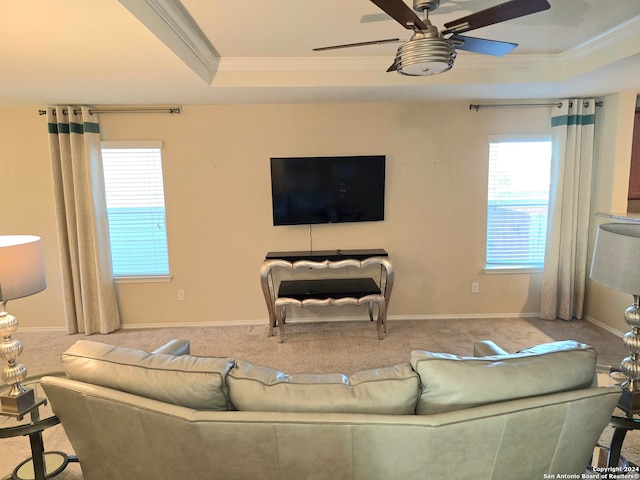 living room with a raised ceiling, carpet flooring, crown molding, and ceiling fan