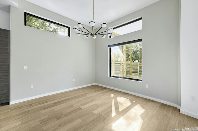 empty room featuring an inviting chandelier, light hardwood / wood-style floors, and a wealth of natural light