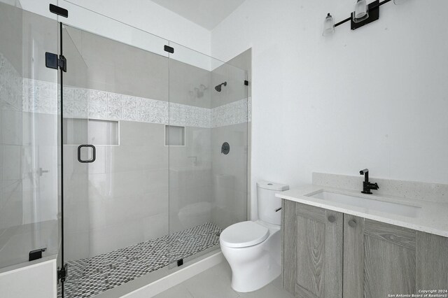 bathroom featuring tile patterned flooring, walk in shower, vanity, and toilet