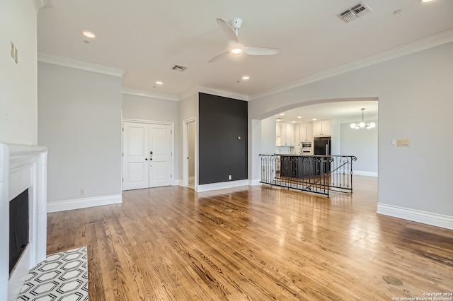 unfurnished living room featuring ceiling fan with notable chandelier, light hardwood / wood-style floors, and crown molding