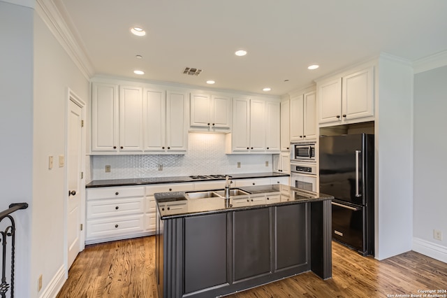 kitchen featuring crown molding, white cabinetry, appliances with stainless steel finishes, decorative backsplash, and hardwood / wood-style floors