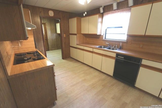 kitchen featuring light hardwood / wood-style flooring, black appliances, wood walls, and sink