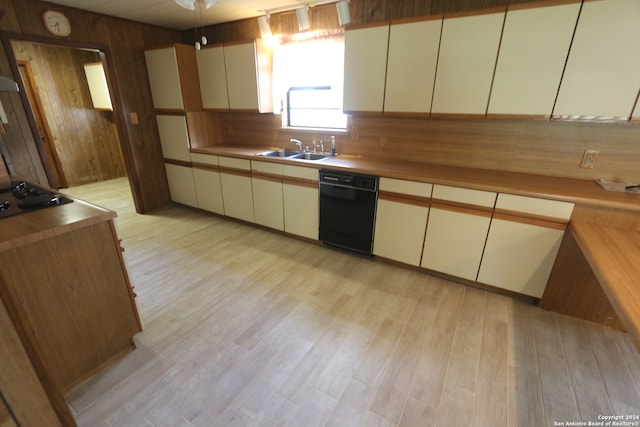 kitchen with wood walls, sink, cream cabinets, light hardwood / wood-style flooring, and black appliances