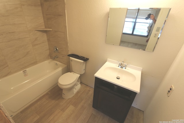 full bathroom featuring wood-type flooring, tiled shower / bath, vanity, and toilet