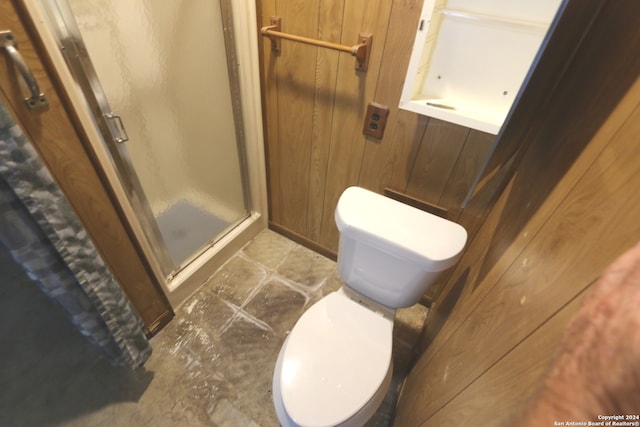 bathroom with walk in shower, wood walls, and toilet