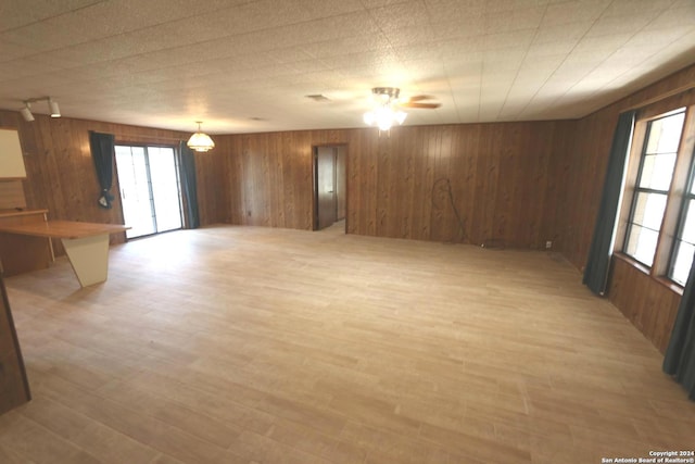 spare room featuring light wood-type flooring, wood walls, and ceiling fan