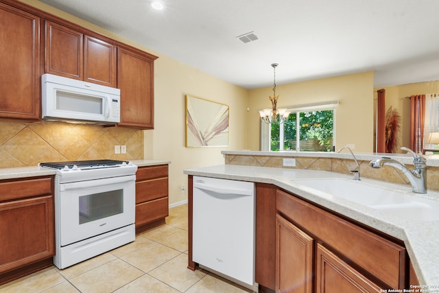 kitchen featuring light tile patterned flooring, white appliances, decorative light fixtures, sink, and a chandelier