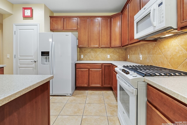 kitchen featuring backsplash, light tile patterned floors, and white appliances